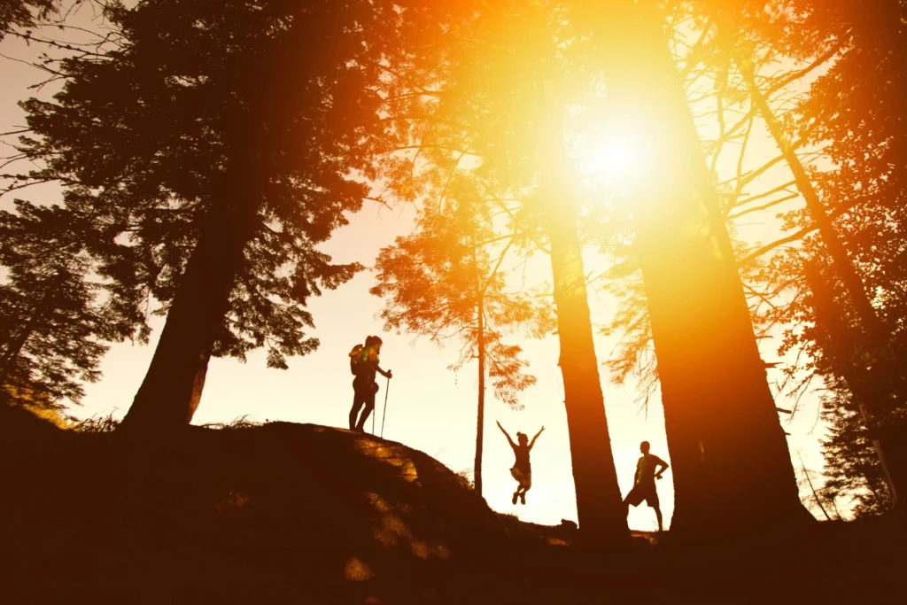 A sunset with three hikers in summer hiking outfits